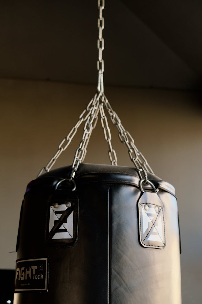 Close-up of a black punching bag with metal chains in a gym setting.